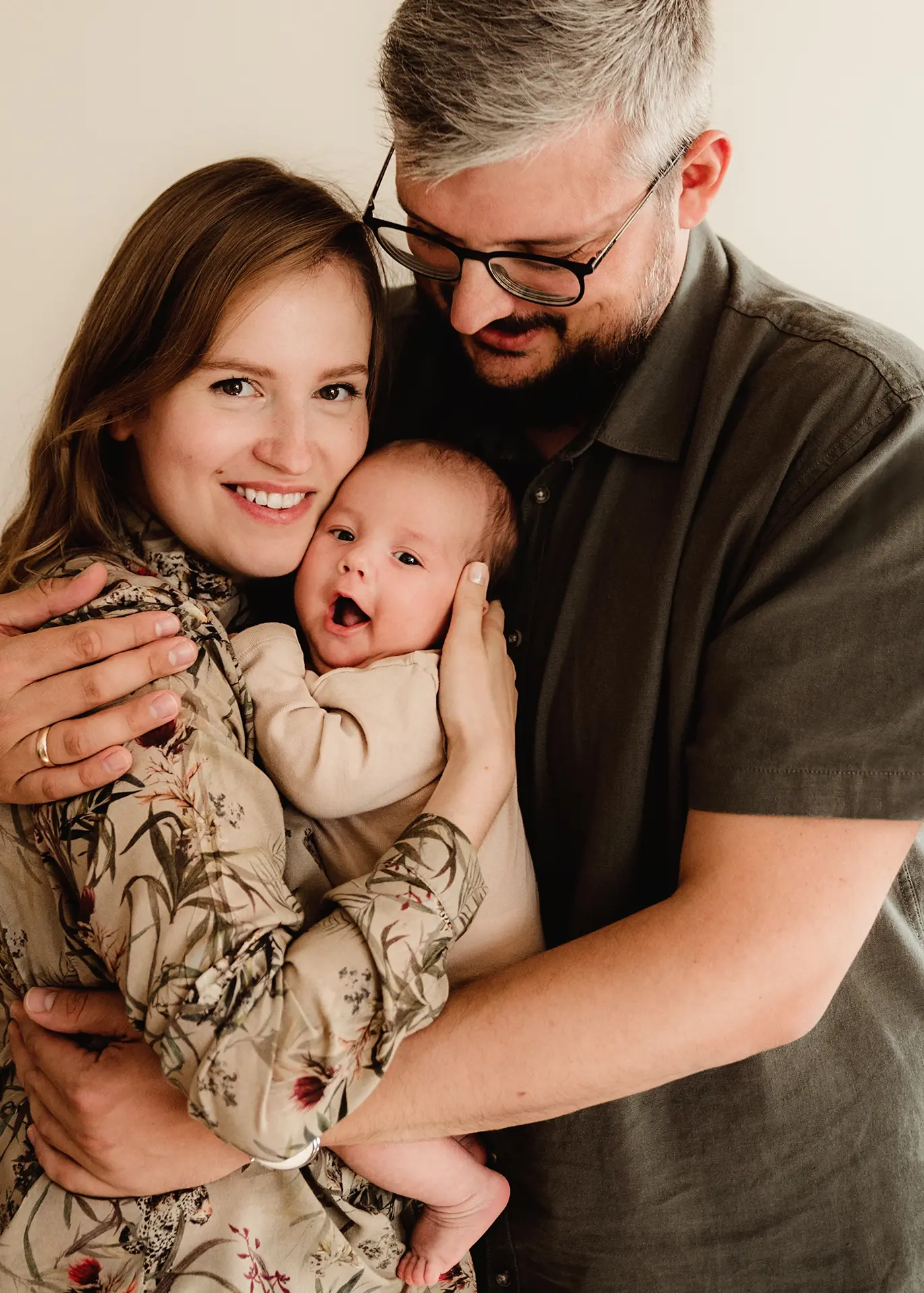 Uśmiechnięci rodzice Agnieszka i Krzysiek tulący noworodka Jerzyka, radosna sesja noworodkowa w domu, autentyczne emocje, fotografia rodzinna Gdynia lifestyle.