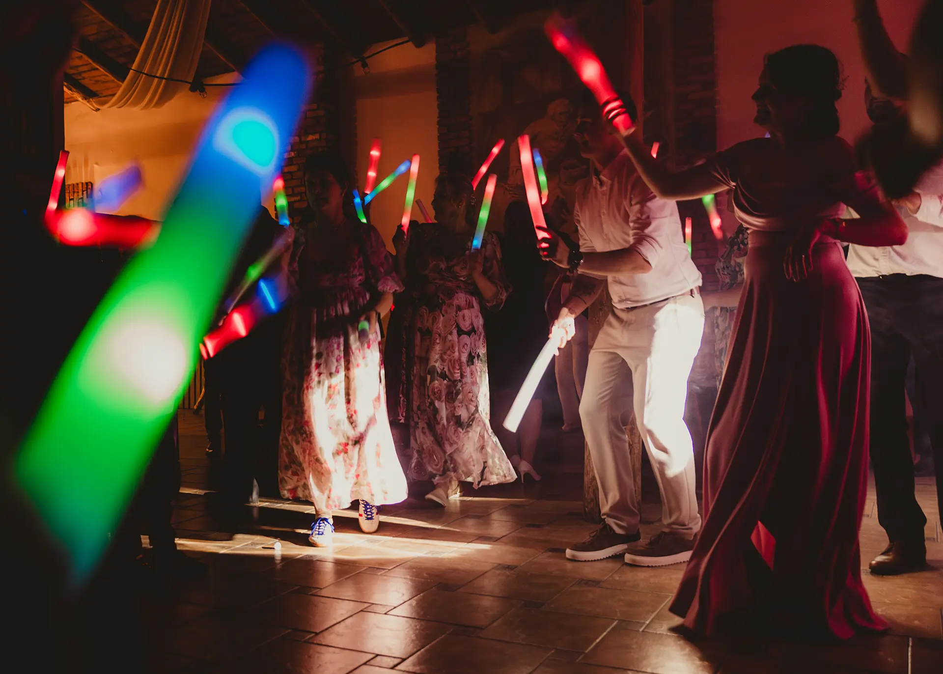 Kolorowa fotografia ślubna, dynamiczne ujęcie gości weselnych tańczących ze świecącymi pałeczkami neonowymi na parkiecie, imprezowa atmosfera w nocy, fotograf Rumia